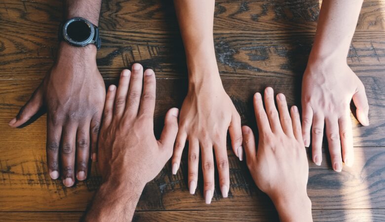 five human hands on brown surface